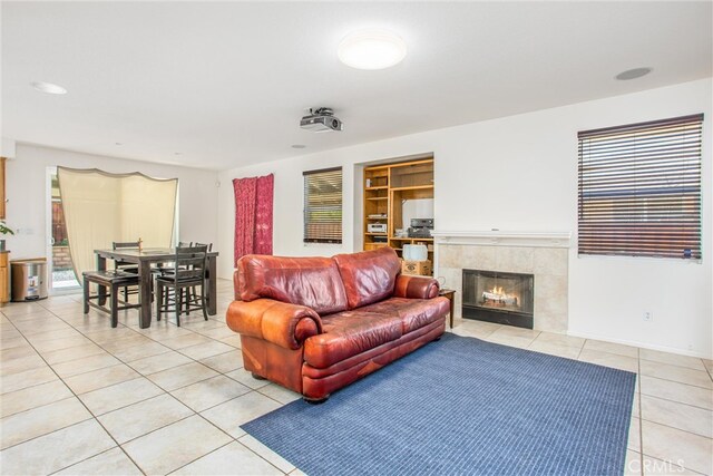 living area with light tile patterned floors, a tiled fireplace, built in features, and a wealth of natural light