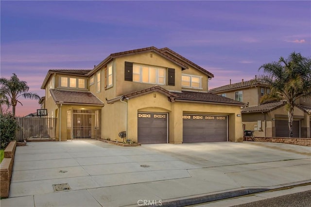 view of front of house featuring an attached garage, fence, a tile roof, driveway, and stucco siding