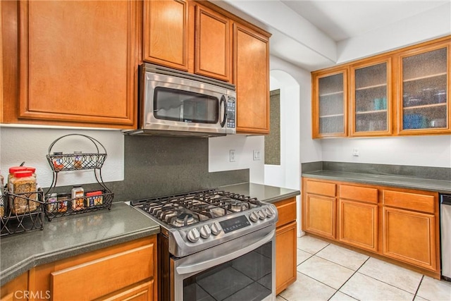 kitchen featuring dark countertops, glass insert cabinets, and stainless steel appliances