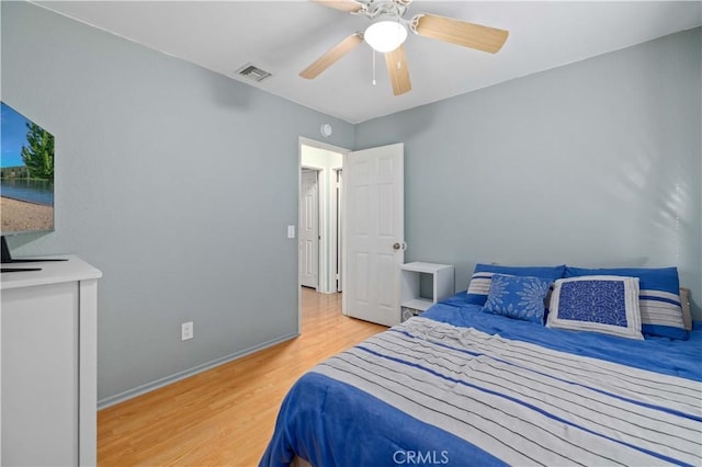 bedroom with a ceiling fan, visible vents, baseboards, and wood finished floors