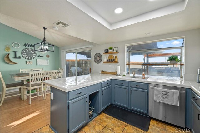 kitchen featuring visible vents, tile countertops, a peninsula, hanging light fixtures, and stainless steel dishwasher