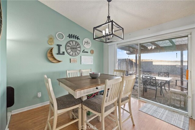 dining area with a textured ceiling, baseboards, and wood finished floors