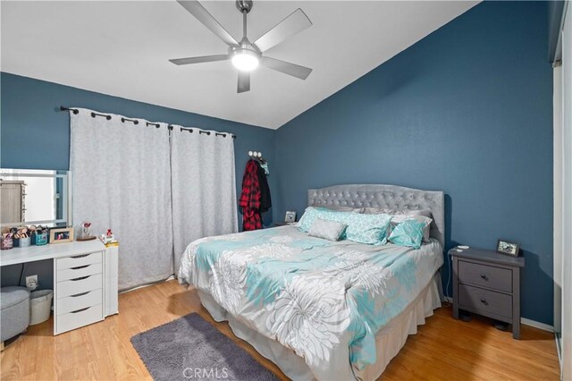 bedroom featuring ceiling fan, vaulted ceiling, baseboards, and wood finished floors