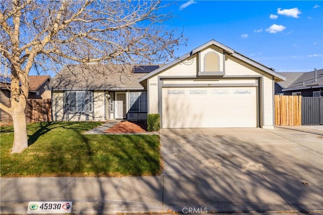 ranch-style house with concrete driveway, an attached garage, roof mounted solar panels, fence, and a front lawn