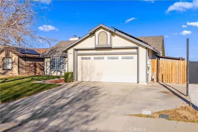 single story home with a garage, fence, driveway, roof mounted solar panels, and a chimney