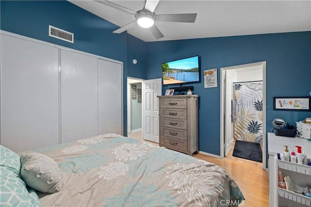 bedroom with lofted ceiling, wood finished floors, visible vents, a ceiling fan, and a closet