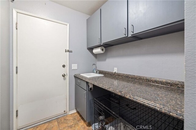 washroom with stone finish flooring, a sink, baseboards, and laundry area