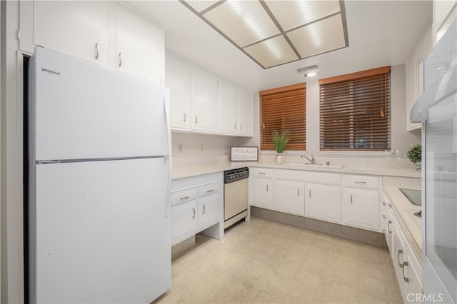 1860 Mckinney Way Unit 21L, Seal Beach, CA 90740 - kitchen with visible vents, dishwashing machine, freestanding refrigerator, light floors, and white cabinetry