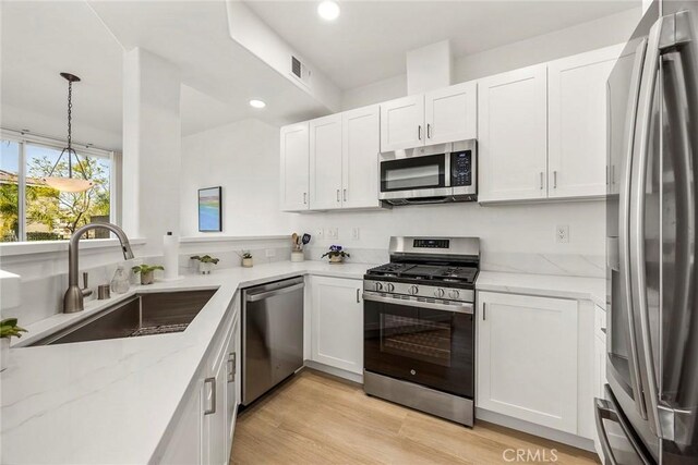 kitchen with stainless steel appliances, a sink, visible vents, and white cabinetry