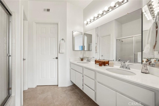 full bathroom with double vanity, a shower stall, visible vents, and a sink