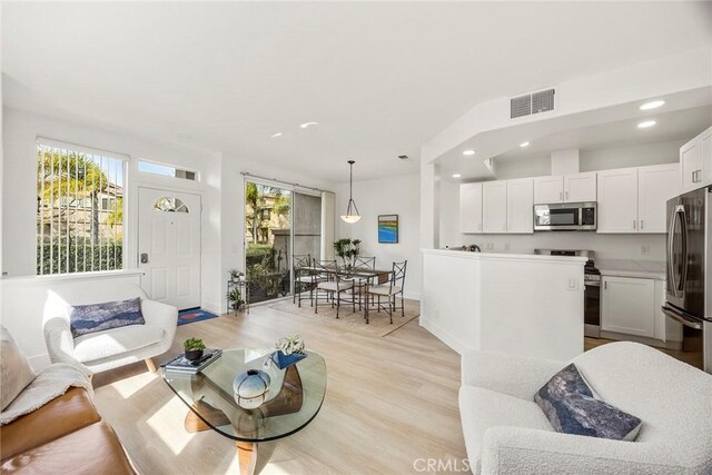 living area with light wood-type flooring, plenty of natural light, visible vents, and recessed lighting