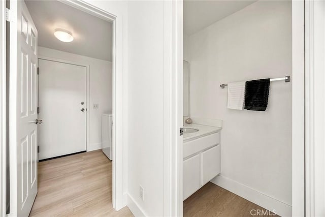 bathroom with separate washer and dryer, wood finished floors, vanity, and baseboards