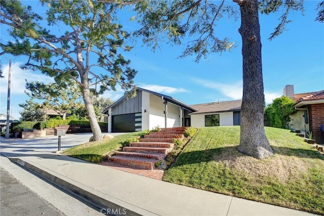 view of front of home with a garage, concrete driveway, board and batten siding, and a front lawn