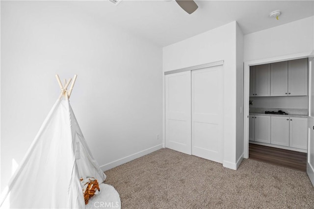 unfurnished bedroom with a ceiling fan, a closet, baseboards, and carpet flooring