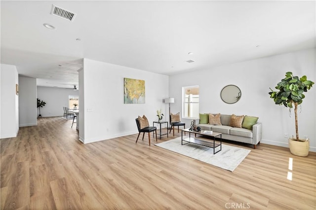 living room featuring light wood-style floors, baseboards, and visible vents