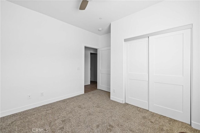 unfurnished bedroom with carpet floors, a ceiling fan, baseboards, and a closet