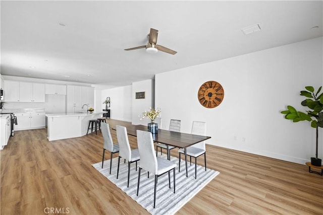 dining space with light wood-style flooring and a ceiling fan