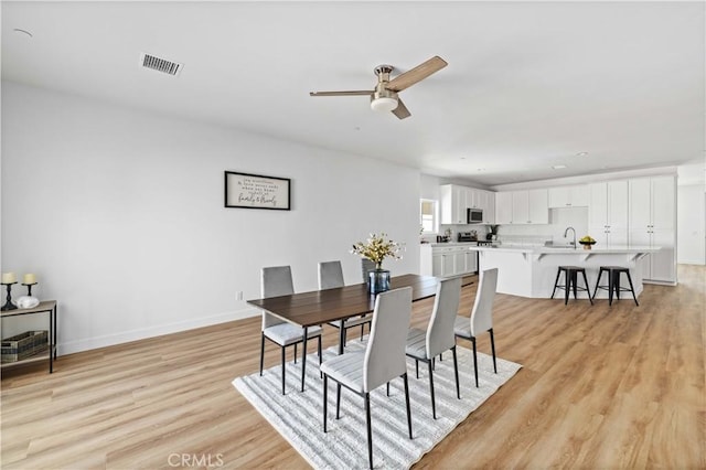 dining space with light wood-style floors, visible vents, ceiling fan, and baseboards