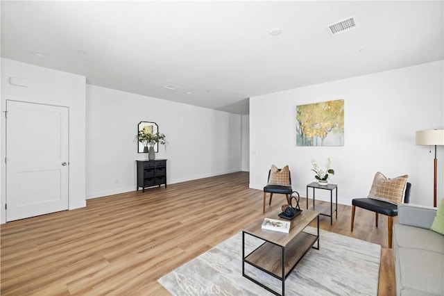 living area with light wood-style flooring, visible vents, and baseboards