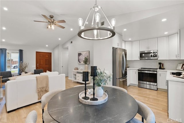 dining room with recessed lighting, vaulted ceiling, light wood-style flooring, and ceiling fan with notable chandelier