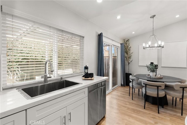 kitchen with lofted ceiling, light wood-style flooring, a sink, white cabinets, and stainless steel dishwasher