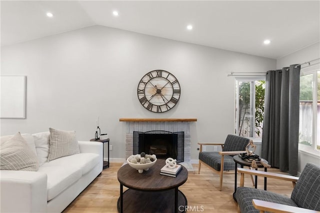 living area featuring light wood finished floors, lofted ceiling, recessed lighting, a brick fireplace, and baseboards