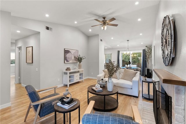 living room with vaulted ceiling, light wood-type flooring, visible vents, and baseboards