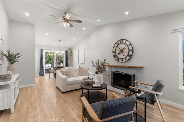 living area featuring vaulted ceiling, light wood finished floors, a brick fireplace, and baseboards