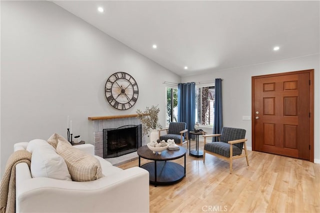 living room featuring lofted ceiling, recessed lighting, a fireplace, and light wood-style floors