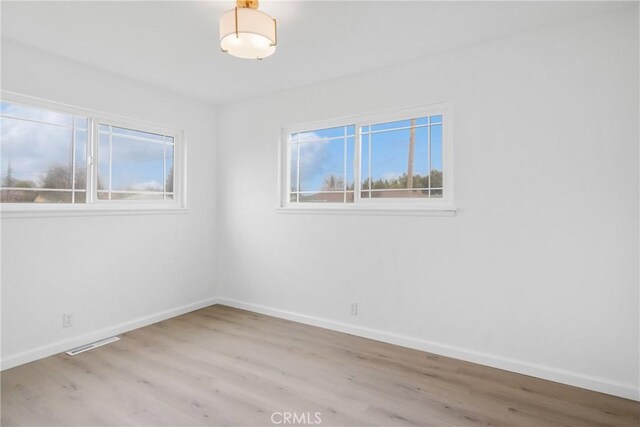 empty room with visible vents, baseboards, and wood finished floors