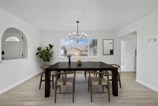 dining space with a wealth of natural light, light wood-style flooring, and a notable chandelier