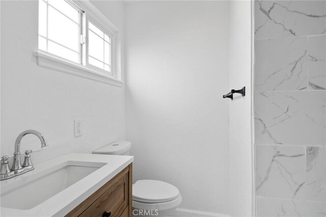 bathroom featuring baseboards, vanity, and toilet