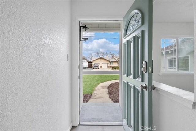 doorway with baseboards and a textured wall