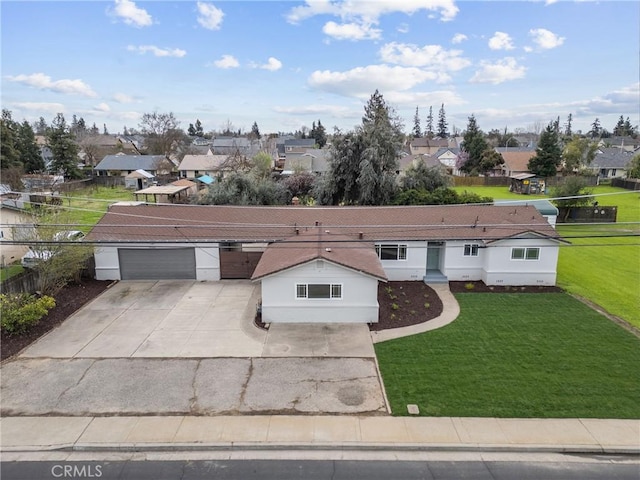 view of front facade featuring an attached garage, fence, concrete driveway, a residential view, and a front lawn