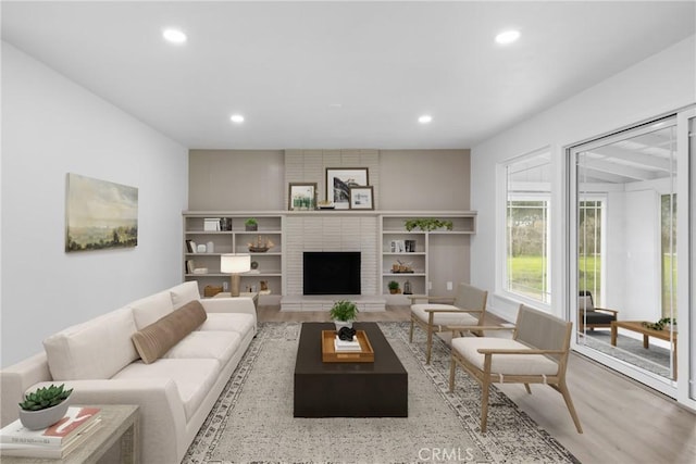 living area with a fireplace, wood finished floors, and recessed lighting