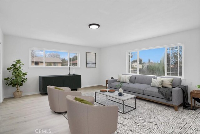 living area with plenty of natural light, light wood-style flooring, and baseboards