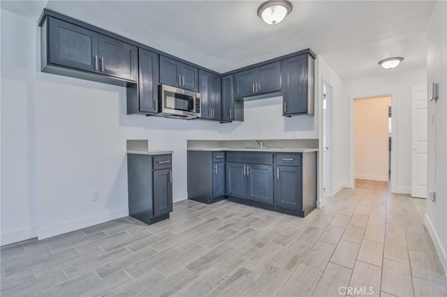 kitchen with wood tiled floor, stainless steel microwave, and a sink