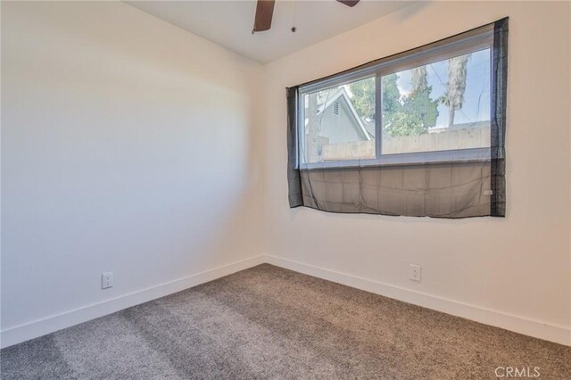 carpeted empty room with baseboards and a ceiling fan