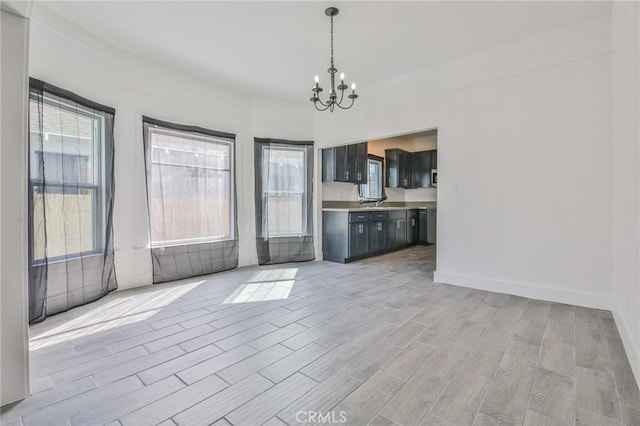 interior space with baseboards, light wood-type flooring, and a notable chandelier