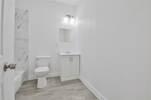 bathroom with toilet, vanity, baseboards, and wood finish floors