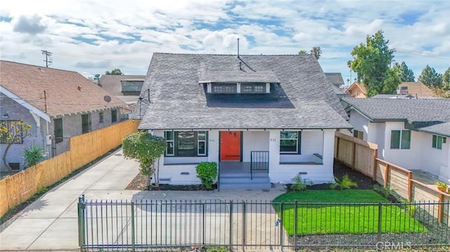 view of front of home featuring a fenced front yard, a front lawn, and a shingled roof