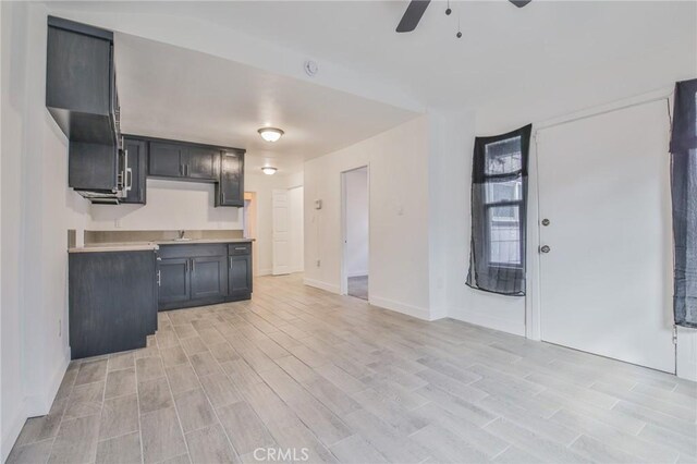 kitchen with light wood finished floors, ceiling fan, baseboards, and light countertops