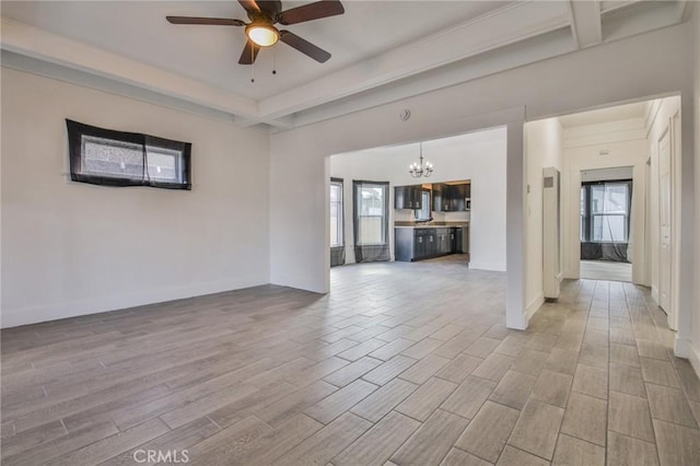 unfurnished living room with ceiling fan with notable chandelier, baseboards, and wood finished floors