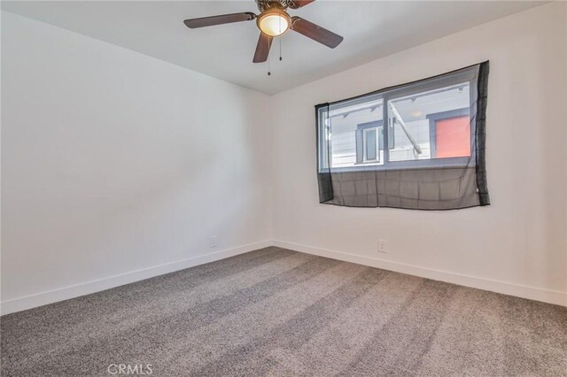 carpeted empty room featuring ceiling fan and baseboards