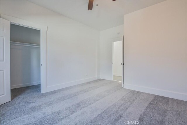 unfurnished bedroom featuring carpet floors, a closet, baseboards, and a ceiling fan