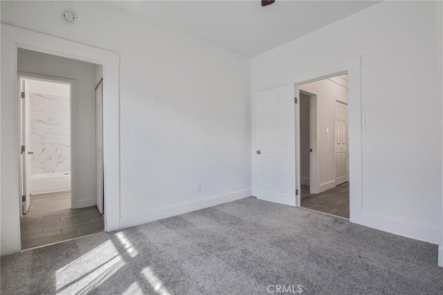 unfurnished bedroom with connected bathroom, baseboards, and carpet flooring