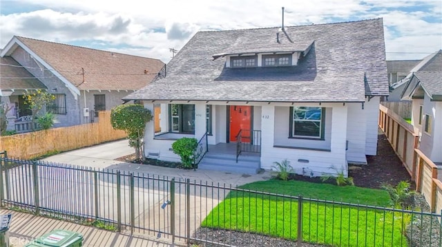 bungalow-style house featuring roof with shingles, a front lawn, and a fenced front yard