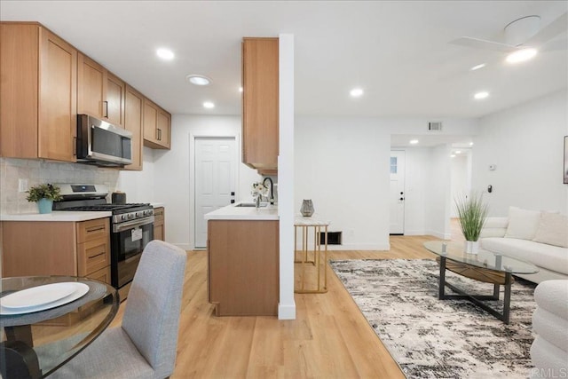 kitchen featuring stainless steel appliances, visible vents, light wood-style flooring, decorative backsplash, and open floor plan