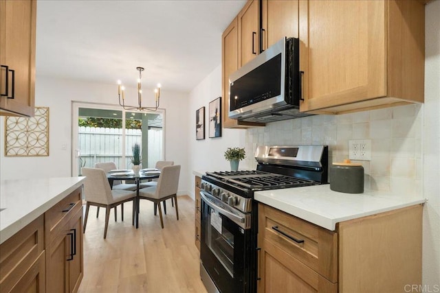 kitchen with stainless steel appliances, light countertops, light wood-style flooring, and decorative backsplash