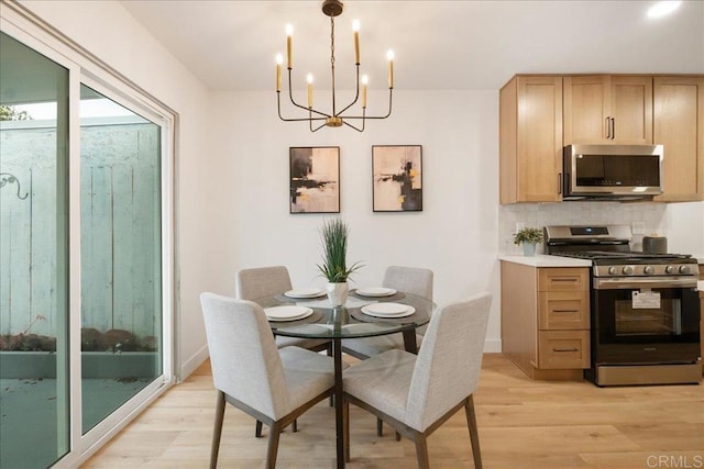 dining room with a chandelier, light wood finished floors, and baseboards